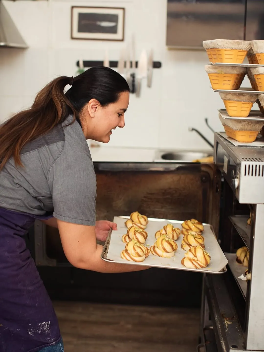 La María posa una safata de rolls al forn.