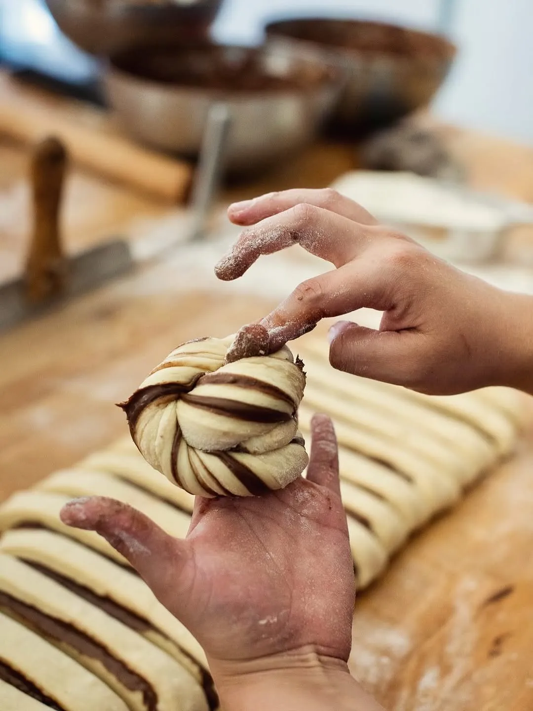 Unes mans fent un nus de massa amb xocolata per a un roll.