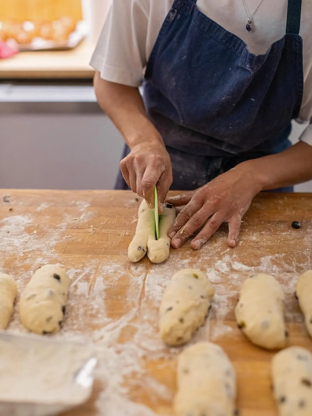 Mans formant les fougasses amb olives sobre el taulell enfarinat.