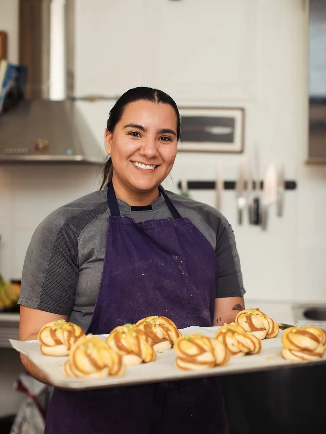 La María, somrient, amb una safata de rolls a l’obrador.